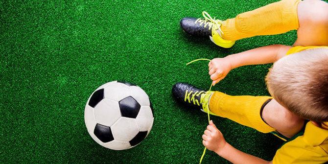 soccer player tying laces on artificial turf